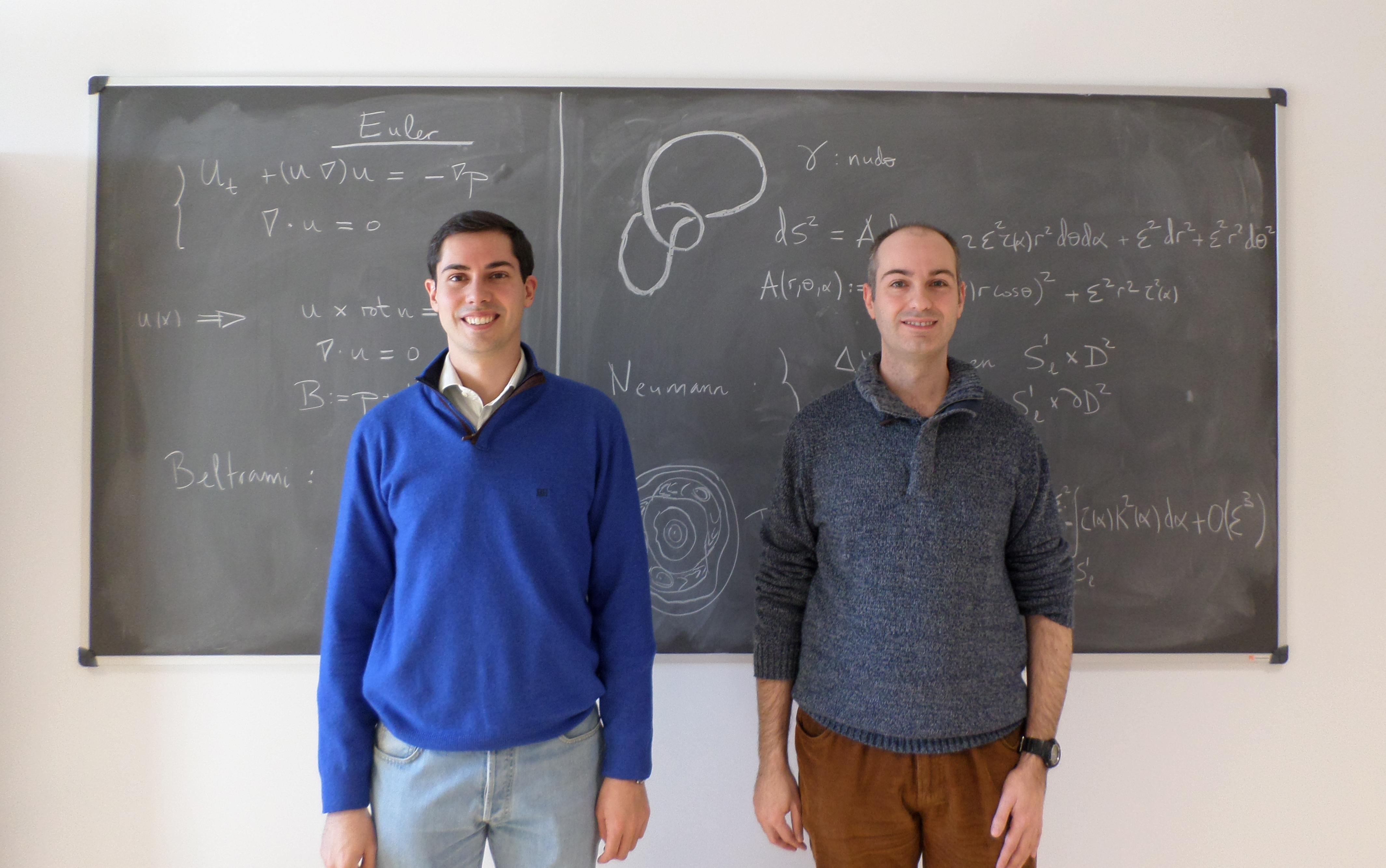 Daniel Peralta (derecha), junto con Alberto Enciso, también investigador del ICMAT, ante una pizarra que muestra un tubo de vorticidad anudado, representación de los resultados que expondrá durante su conferencia